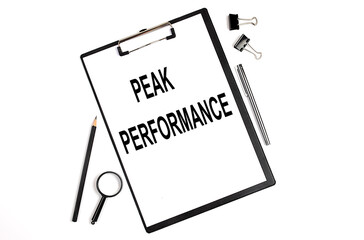 On a white background magnifier, a pen and a sheet of paper with the text PEAK PERFORMANCE . Business concept