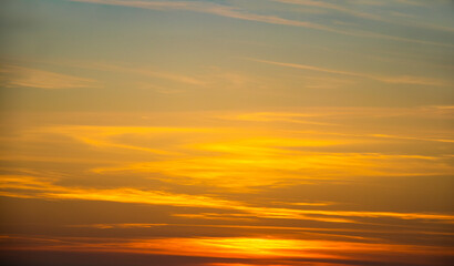 Brilliant streaked  sunset sky with oranges and yellow fading to light turpouise at top - sun shining through low on the horizon.
