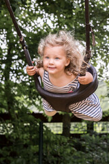 petite fille joue sur une balançoire, elle se balance et vole.