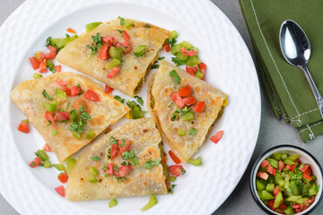 Veggie quesadilla mexican dish prepared with tortilla and filled with vegetables like corn, pepper and tomatoes.
