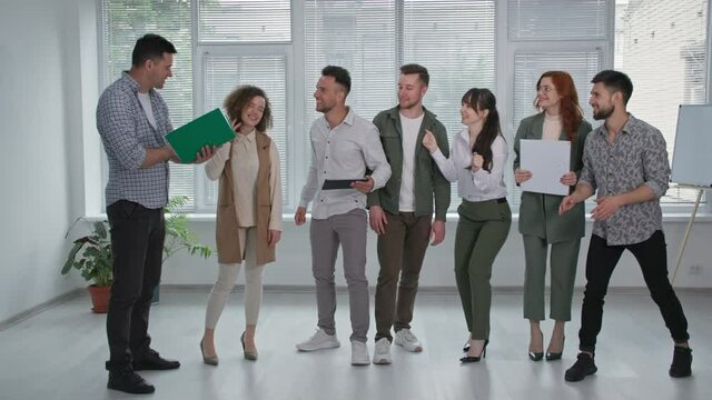 business team, joyful male and female colleagues have fun with good news jumping and laughing in office