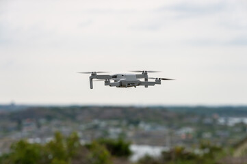 Fototapeta na wymiar Drone in flight, hovering, with visible propellers in movement. Photo and video shooting from the sky. Blurred background with copy space and place for space.