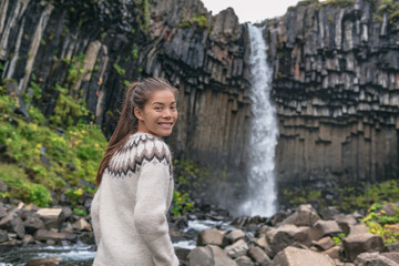 Portrait of woman on Iceland. Hiker enjoying Svartifoss waterfall. Female is visiting famous...