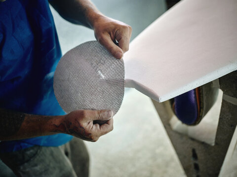 Man with abrasive paper grinding board
