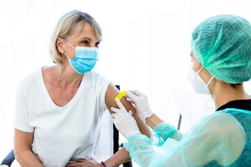 woman wearing mask getting vaccinated concept of coronavirus vaccination mask grown woman approved for covid-19 vaccination at the hospital. Female doctor immunizes against virus with medical plaster.