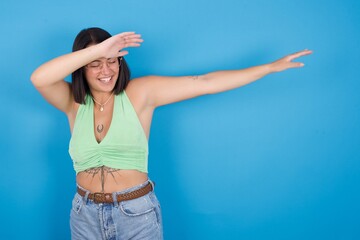 Photo of funky young beautiful tattooed girl wearing green top standing against blue background...