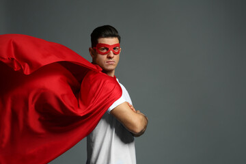 Man wearing superhero cape and mask on grey background. Space for text © New Africa