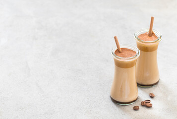 Milk cocktail with coffee cream in a glass with a bamboo straw on a light gray background copy space