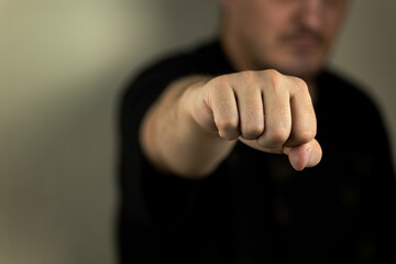 The hand is clenched into a fist for a blow, The concept of demonstrating aggression, fighting posture. Close-up, selective focus, blur.