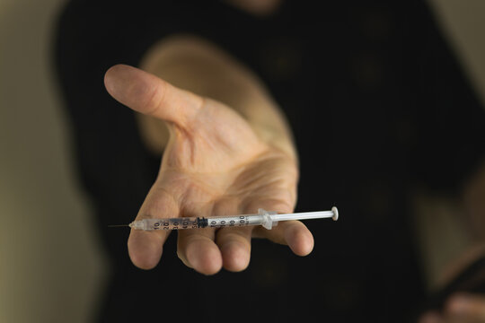 The addict holds a syringe with drugs in his hand in front of him. The concept of drug addiction. A drug addict, a man with a syringe.