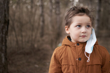 Portrait of boy that takes off his protective mask after quarantine in forest