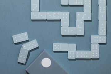 Light Blue wood domino pieces on light blue background. Leisure games concept.