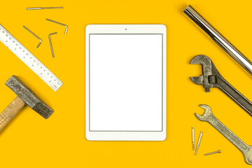 Fix list mockup concept with tablet blank white screen and tool equipment, flat lay and yellow background top view photo, copy space