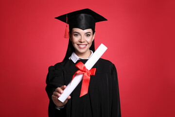 Happy student with graduation hat and diploma on red background