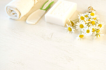 Hygiene product on a light background. Fresh chamomile flowers. Natural antioxidant, protection against bacteria - white soap with chamomile. Spa
