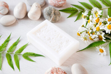 Fototapeta na wymiar Hygiene product on a light background. Fresh chamomile flowers. Natural antioxidant, protection against bacteria - white soap with chamomile. Spa