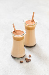 Milk cocktail with coffee cream in a glass with a bamboo straw on a light gray background	