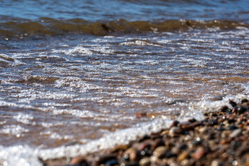 sparkling waves in the Baltic Sea on the shore of which there are many small stones