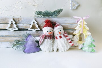 Toys snowmen, Christmas tree on a light wooden background, Merry Christmas, concept of congratulations, postcards