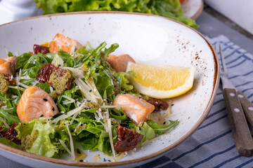Salad with salmon, dried tomatoes, cheese and fresh greens.