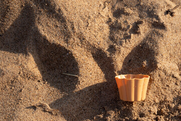 a plastic bowl dropped in the fine sand of the beach