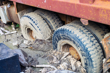 The rear wheels of the three-axis truck got stuck in the mud after the deluge.