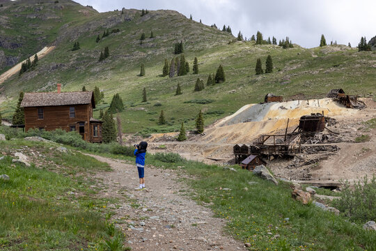 Young boy taking pictures of abandoned homes in Animas Forks ghost town in Colorado.