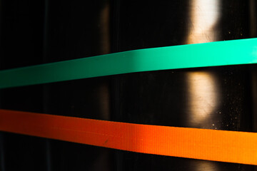 The transport belts in green and orange are stretched against a black background.