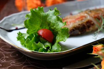 Baked juicy meat in glaze. Greens. A tomato
