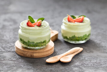 Summer dessert of spinach biscuits with cottage cheese cream with green tea matcha with fresh strawberries in a glass jar on a dark gray background