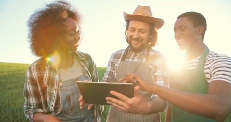 Group of multiracial farmers or technologists inspecting field process while using tablet computer for engineering. Cooperation and agriculture concept