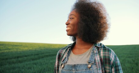Portrait of multiracial female farmer walking through the large green multi-colored rural field....