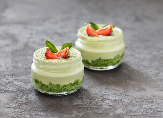 Cheesecake green tea matcha without baking with fresh strawberries in a glass jar on a dark gray background