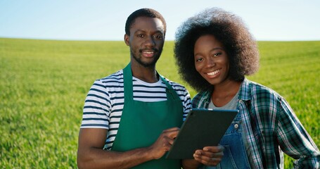 Male and female multiracial engineers using digital tablet while inspecting greenhouse organic farm business construction. Multi-sex farmers. Man and woman. Agronomy concept