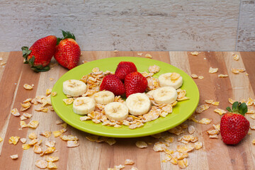 Strawberry, banana and cereals on a green dish