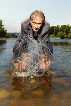 Manager in grey suit became crazy of hot weather and cooling in river