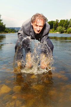 Manager in grey suit became crazy of hot weather and cooling in river