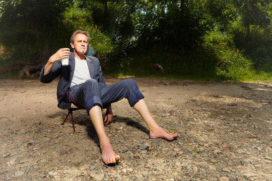 Manager in grey suit became crazy of hot weather and cooling in river