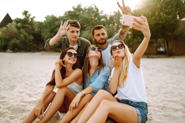 Selfie time. Group of friends taking selfie with the phone. Young friends enjoy summer party together at the beach. Friendship and lifestyle concepts.