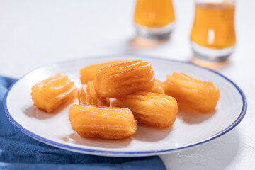 Bosnian and Turkish dessert called Tulumba served on a brught background with cup of tea