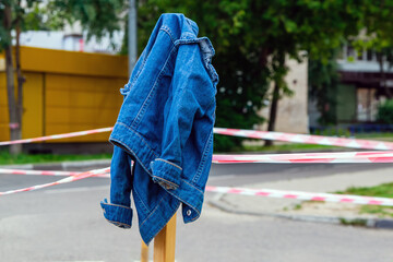 A lost denim children's jacket hangs on a fence pole.