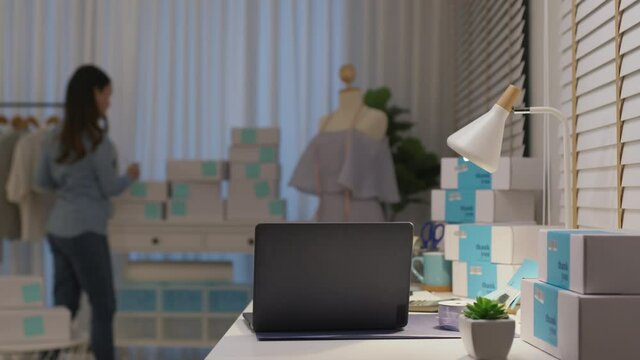 Digital tablet computer or laptop on home office desk with asia freelance seller woman happy packing check busy work in fashion studio SME online store social e-commerce sale page service web support.