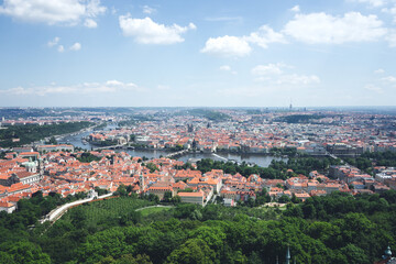 Naklejka na ściany i meble Panorama of city with a wide river in summer. River in a European city with red tile roofs. View of the cozy streets of the old Czech city on a background of blue sky.