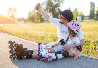 Young father and daughter roller skating and make selfie with mobile phone. - obrazy, fototapety, plakaty