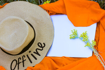 A straw hat with a written word Offline. An orange rag background, a gray laptop flatly. Lack of...