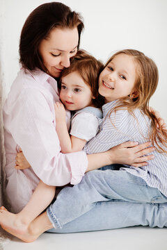 beautiful happy family sit on floor and cuddle in white photo studio.