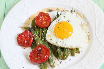 Scrambled eggs with tomatoes and green beans on green wooden background