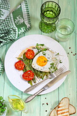 Scrambled eggs with green beans, tomatoes with white wine on a green wooden background