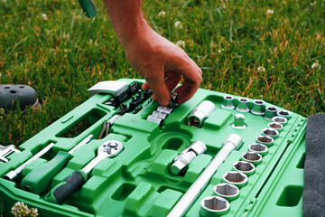 Chrome mechanics tools set. Close-up photo of a set of sockets with a screwdriver and a ratchet in a green plastic case against a background of green grass. Auto tool.