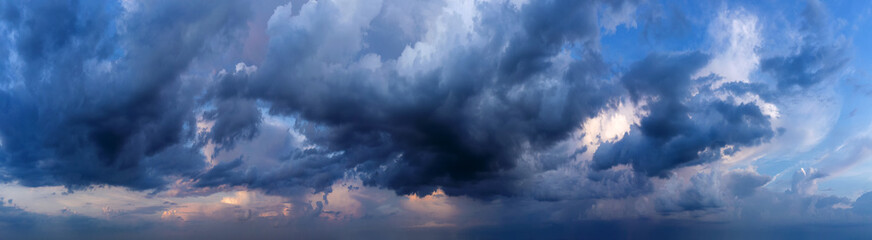 Dramatic sky background with dark rainy clouds at sunset.